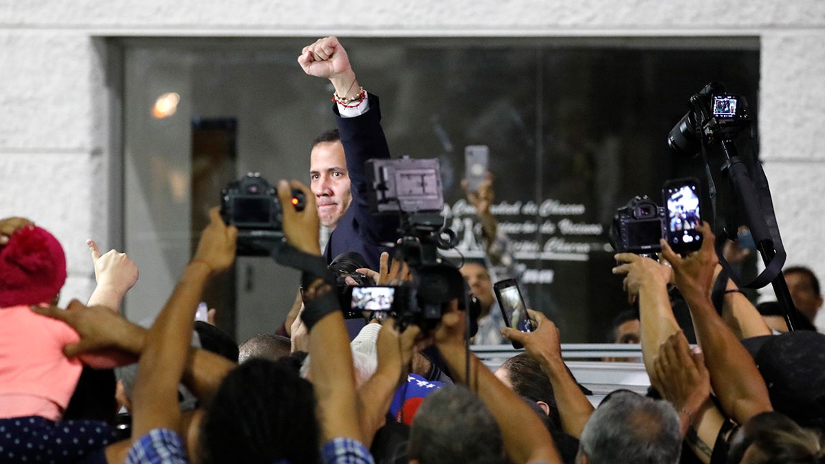Surrounded by the media, opposition leader Juan Guaido pumps his fist after a rally at Bolivar Plaza in Chacao, Venezuela, Tuesday, Feb. 11, 2020. Guaido returned home from a tour of nations that back his effort to oust socialist leader Nicolas Maduro. (AP Photo/Ariana Cubillos)