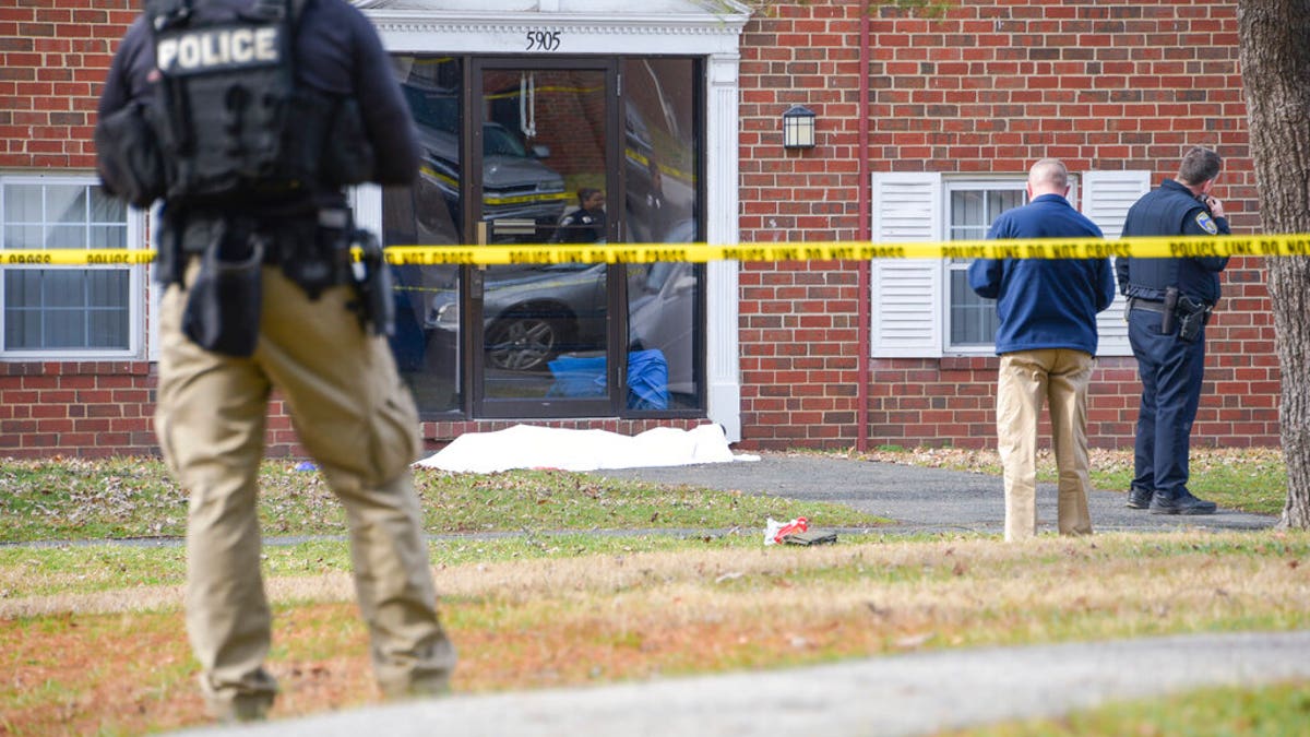 Law enforcement personnel work at the scene which appears to show a body covered under a white blanket outside of an apartment, Wednesday, Feb. 12, 2020, in Baltimore.