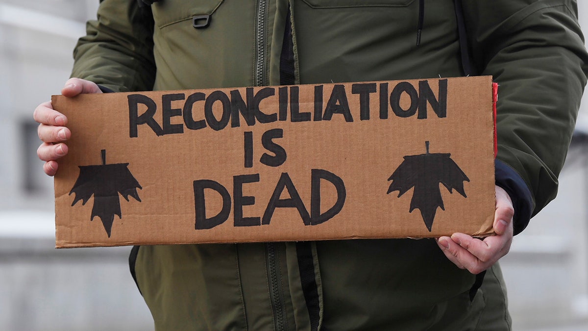 A protester carries a sign as he and others were marching on a street in Ottawa, Ontario, Wednesday, Feb. 12, 2020. The protesters are standing in solidarity with the Wet'suwet'en hereditary chiefs opposed to a Canada gas pipeline in northern British Columbia. (Adrian Wyld/The Canadian Press via AP)