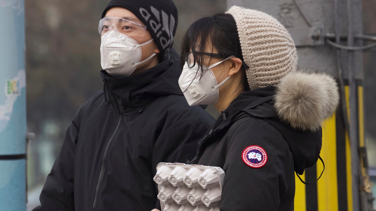 Residents wearing masks wait at a traffic light in Beijing, China Thursday, Feb. 13, 2020. (AP Photo/Ng Han Guan)
