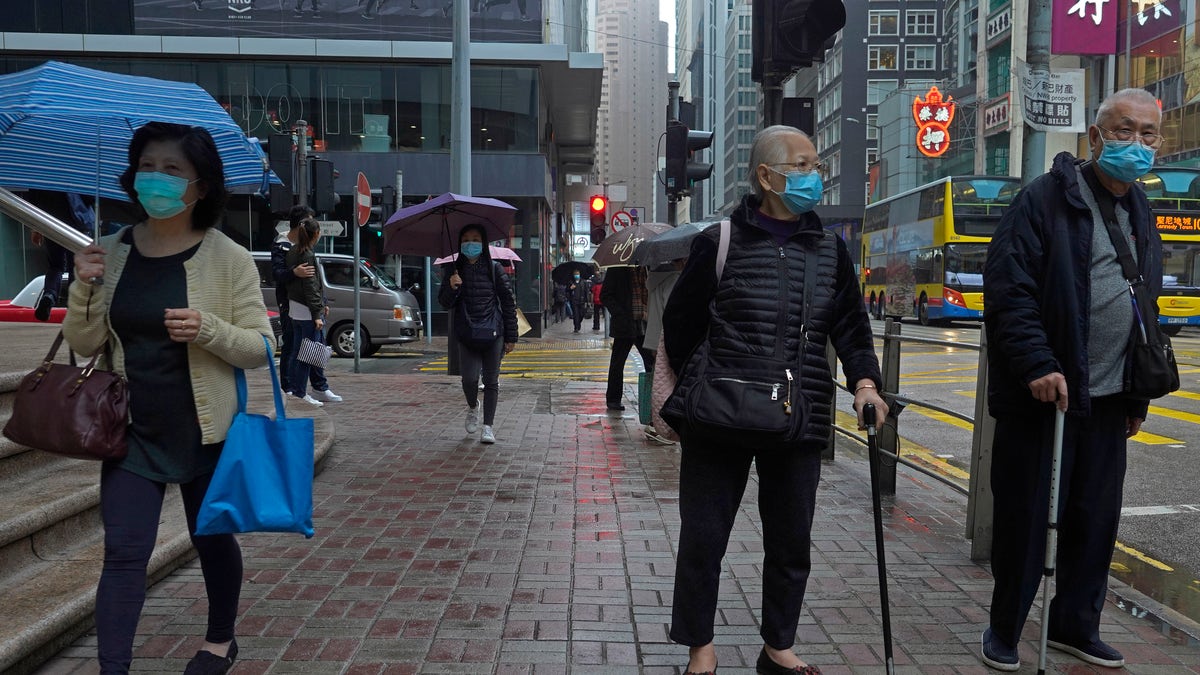 People wearing protective face masks walk on a street in the rain in Hong Kong, Friday, Feb. 14, 2020. COVID-19 viral illness has sickened tens of thousands of people in China since December. (AP Photo/Vincent Yu)