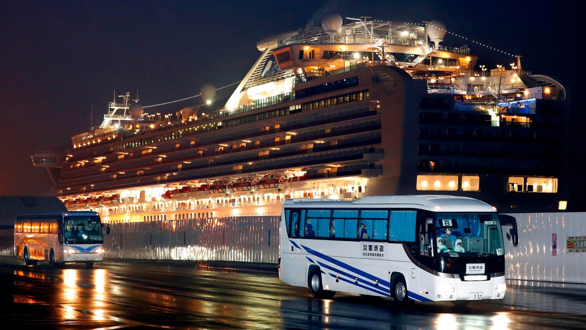 Buses carrying U.S. passengers who were aboard the quarantined cruise ship the Diamond Princess, seen in the background. (Jun Hirata/Kyodo News via AP)