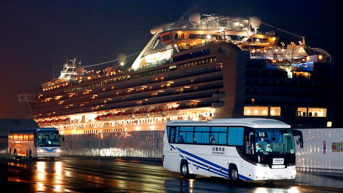 Buses carrying U.S. passengers who were aboard the quarantined cruise ship the Diamond Princess, seen in the background. (Jun Hirata/Kyodo News via AP)