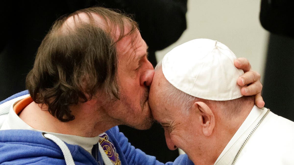 Pope Francis is kissed by a man during his weekly general audience, at the Pope Paul VI hall, at the Vatican, Wednesday, Feb. 19, 2020. 