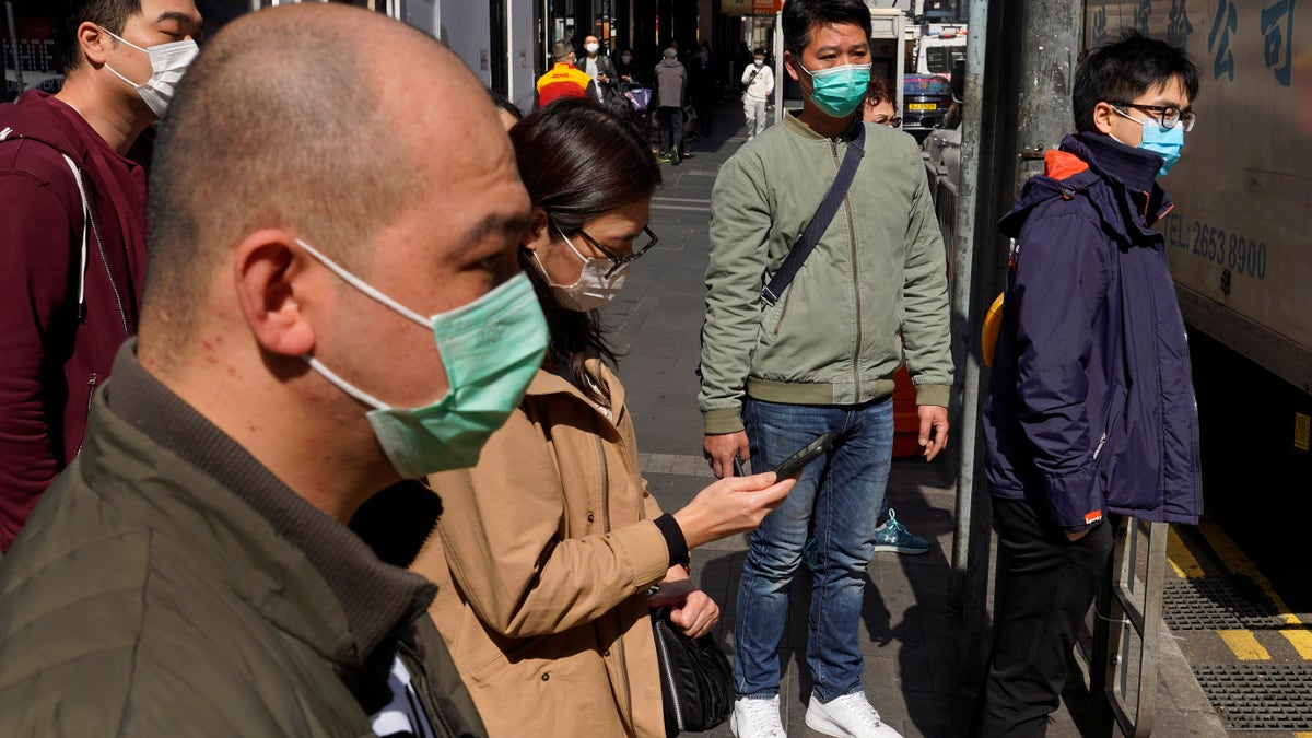 People wearing face masks walk on a down own street in Hong Kong Friday, Feb. 21, 2020. COVID-19 viral illness has sickened tens of thousands of people in China since December. (Associated Press)