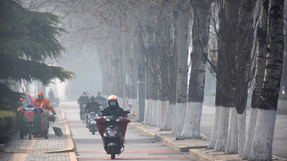 People wear face masks as they ride along a road in Beijing, Friday, Feb. 21, 2020. (Associated Press)