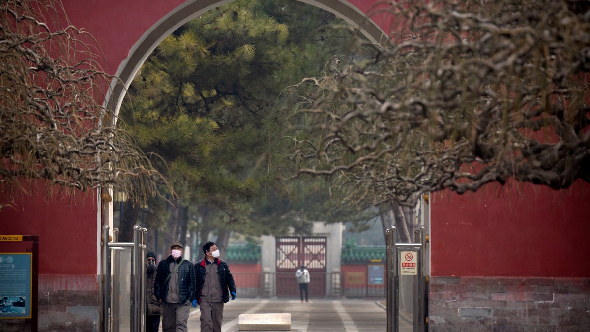 People wearing face masks walk through a public park in Beijing, Friday, Feb. 21, 2020. (Associated Press)