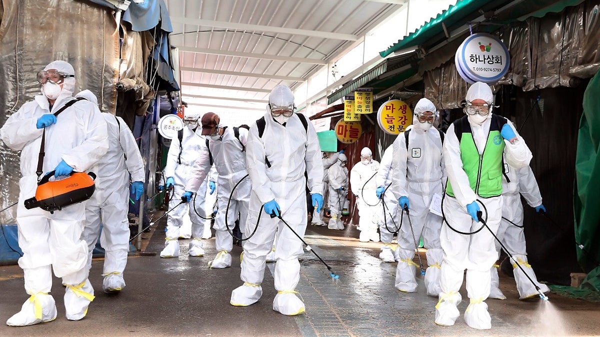 Workers wearing protective suits spray disinfectant as a precaution against the coronavirus at a market in Bupyeong, South Korea, on Monday. South Korea reported another large jump in new virus cases Monday a day after the president called for "unprecedented, powerful" steps to combat the outbreak that is increasingly confounding attempts to stop the spread. (Lee Jong-chul/Newsis via AP)