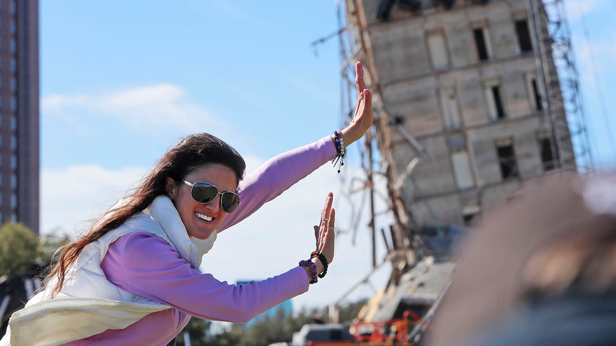 Megan Dority poses for a photo with the so called "Leaning Tower of Dallas" as a crew works to topple the structure north of downtown Dallas, Monday, Feb. 24, 2020. 