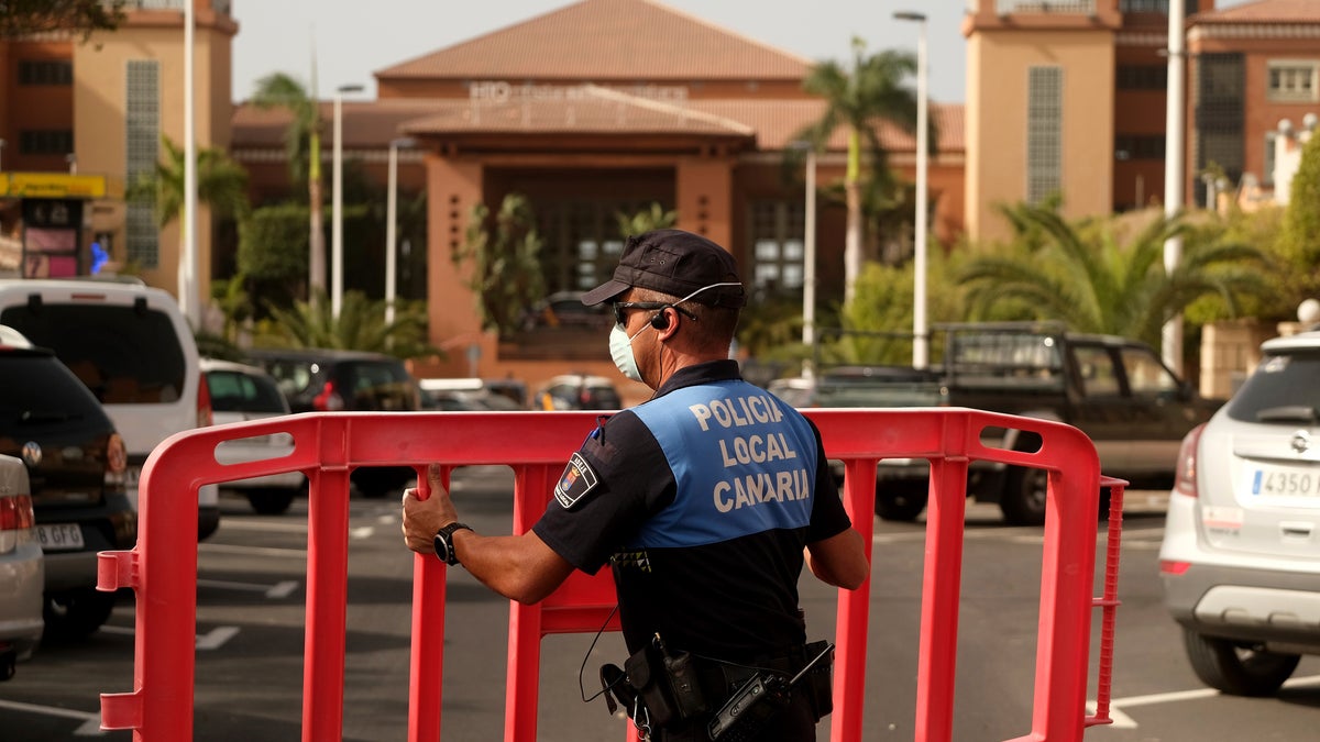 A Spanish police officer sets a barrier blocking access to the H10 Costa Adeje Palace hotel in Tenerife.