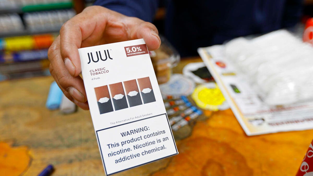 In this June 17, 2019, file photo, a cashier displays a packet of tobacco-flavored Juul pods at a store in San Francisco. 