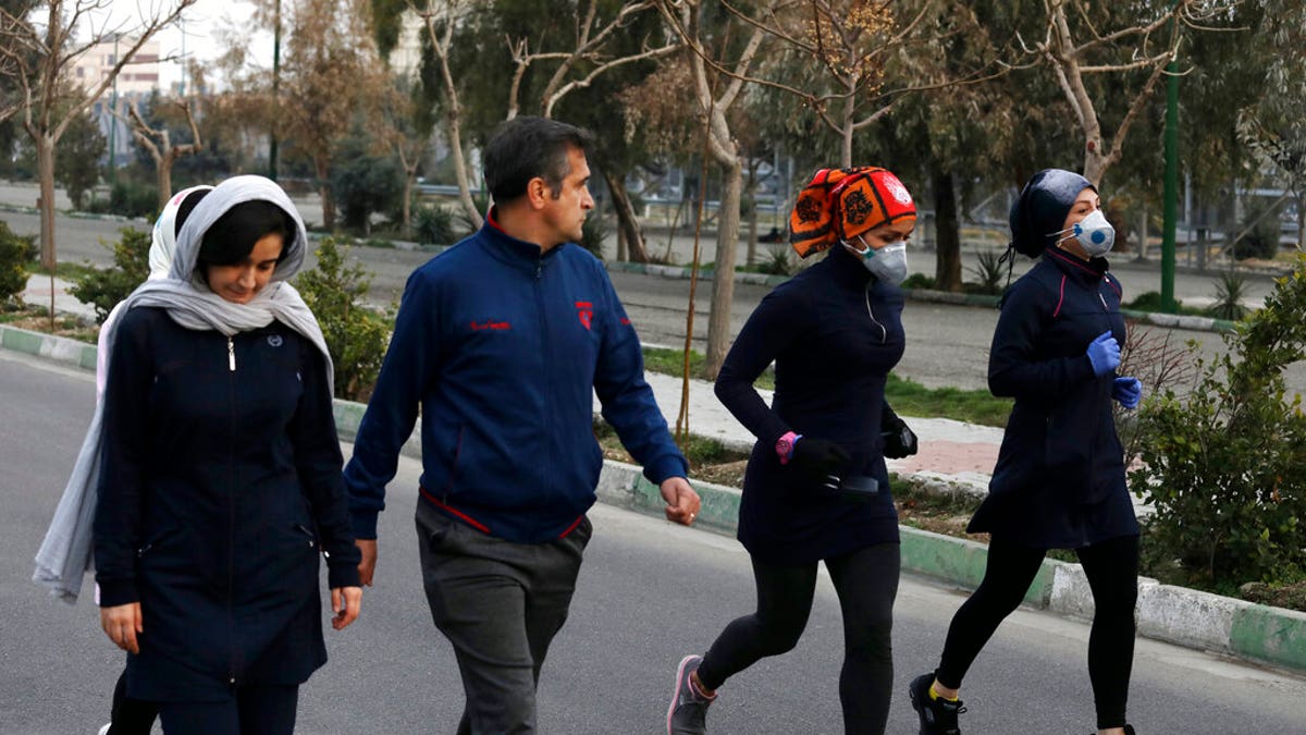 Two women jog with face masks on as others walk while enjoying their weekend afternoon at Pardisan Park in Tehran, Iran, Friday, Feb. 28, 2020. Iranians in Tehran on Friday found time to enjoy their weekend, even as authorities canceled Friday prayers and closed universities, schools and parliament over fears about the new coronavirus. 