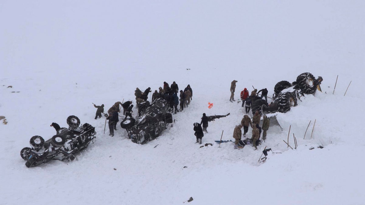 Emergency service members dig in the snow around at least three overturned vehicles, near the town of Bahcesehir, in Van province, eastern Turkey, Wednesday, Feb. 5, 2020.
