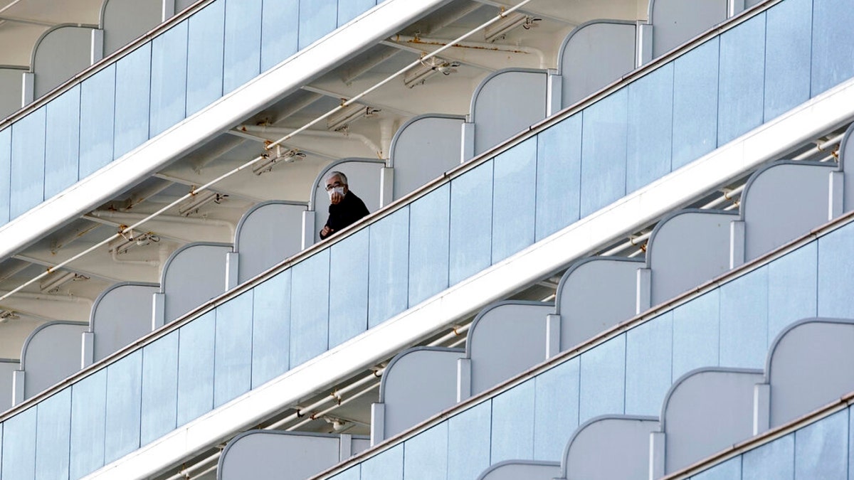 A quarantined passenger stands outside on the balcony of the Diamond Princess on Feb. 6.