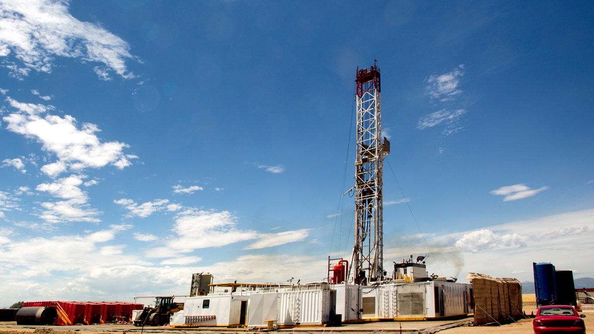 Una perforadora de fracking en un lugar remoto de las montañas con nubes difusas en el cielo al anochecer. La Plataforma de Fracking está realizando una operación de fracking para liberar petróleo crudo y gas natural atrapados en el oleoducto hacia una refinería.