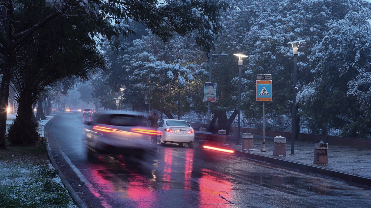 Fresh snow falls while motorists drive through Abu Nawas street in central Baghdad, Iraq, Tuesday, Feb. 11, 2020.