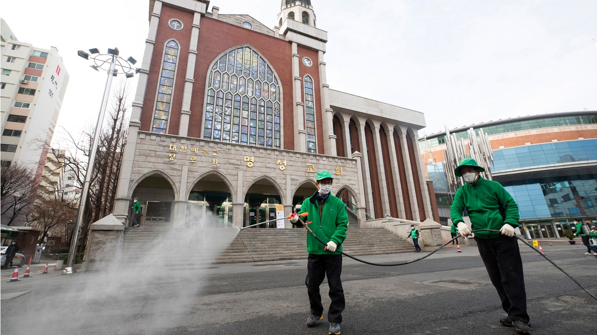 Workers wearing face masks spray disinfectant as a precaution against the new coronavirus in front of Myungsung Church in Seoul, South Korea, Wednesday, Feb. 26, 2020. (Yun Dong-jin/Yonhap via AP)