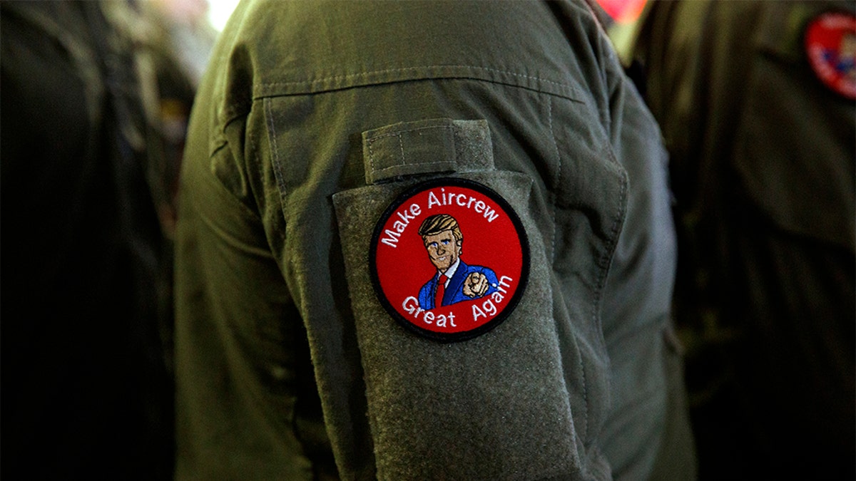 A service member wears a patch that says "Make Aircrew Great Again" as they listen to President Donald Trump speak to troops at a Memorial Day event aboard the USS Wasp in Yokosuka, Japan. The patch includes a likeness of Trump. (AP Photo/Evan Vucci)
