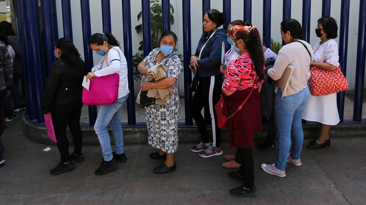 Women wear masks over their mouths as a precaution against the spread of the new coronavirus as they wait to enter as visitors the national hospital that specializes in respiratory diseases, the INER, in Mexico City, Friday, Feb. 28, 2020. Mexico's assistant health secretary announced Friday that the country now has confirmed cases of the COVID-19 virus. (AP Photo/Fernando Llano)