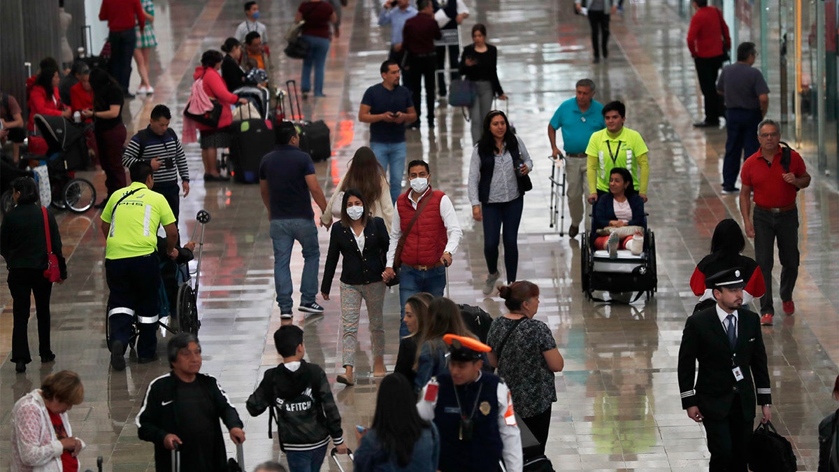 A couple wears protective masks as a precaution against the spread of the new coronavirus at the airport in Mexico City, Friday, Feb. 28, 2020. Mexico assistant health secretary announced Friday that the country now has confirmed cases of the COVID-19 virus. (AP Photo/Marco Ugarte)