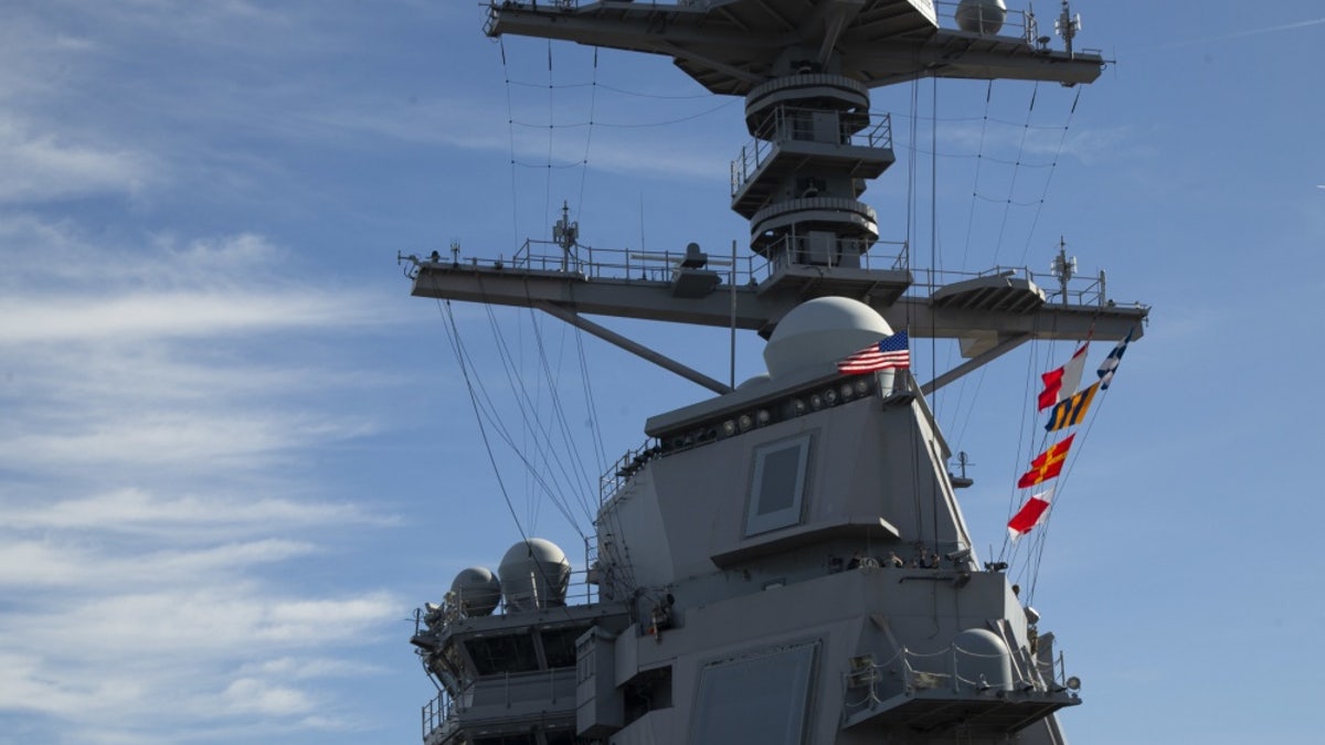 USS Gerald R. Ford (CVN 78) raises the American flag on its mast as the ship get underway,.