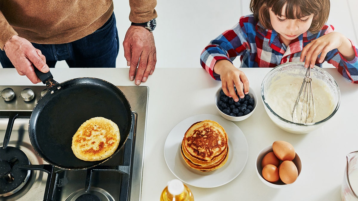 Boy makes pancakes with father