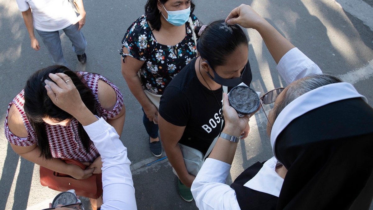 Catholic nuns sprinkle ash on the head of devotees during Ash Wednesday rites Feb. 26, 2020 in Paranaque, metropolitan Manila, Philippines. (AP Photo/Aaron Favila)