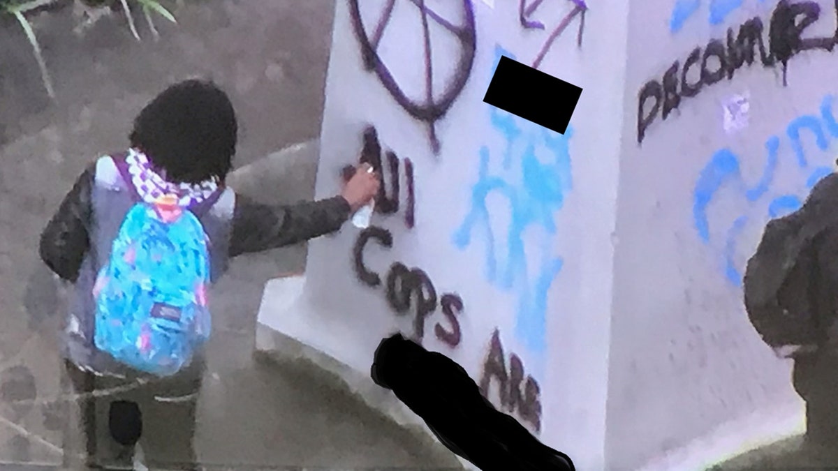 A person can be seen vandalizing a war memorial during a demonstration in downtown Portland, Ore. on Saturday.