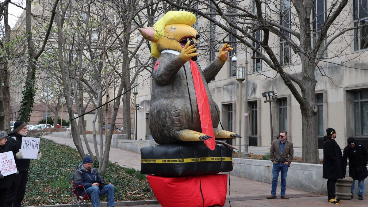 Anti-Stone protesters stand by a giant, blow-up rat version of President Trump.