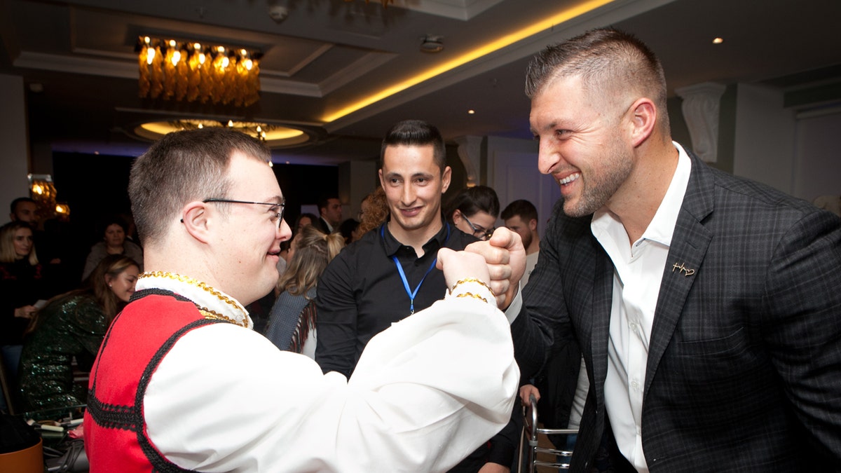 Tim Tebow fist bumps a guest at the "Night to Shine" in Albania.