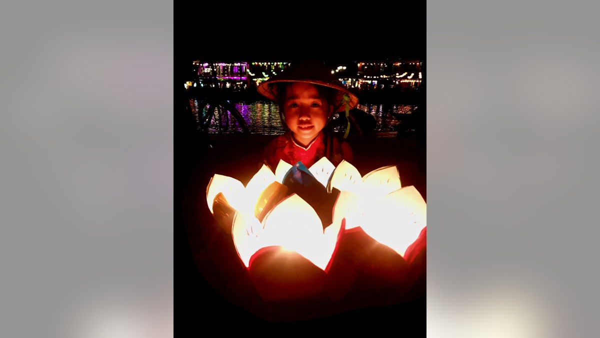A young girl in Hoi An sells lanterns on what was once a bustling lantern-lit riverwalk.