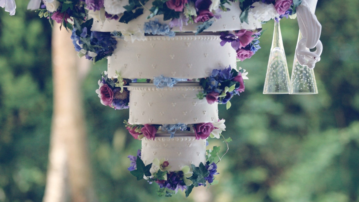 An elegant catered white wedding cake with 3 tiers and latticed frosting.