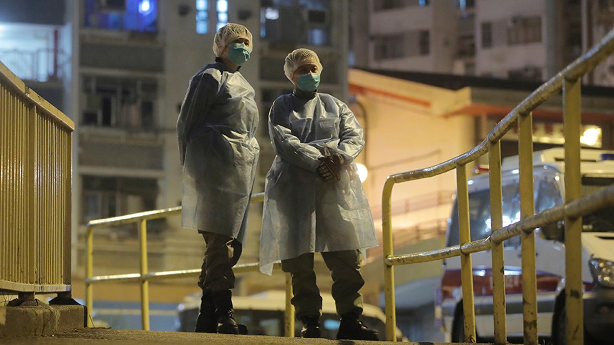People wearing protective suits stand near the Cheung Hong Estate, a public housing estate, during the evacuation of residents in Hong Kong on Tuesday. (AP)