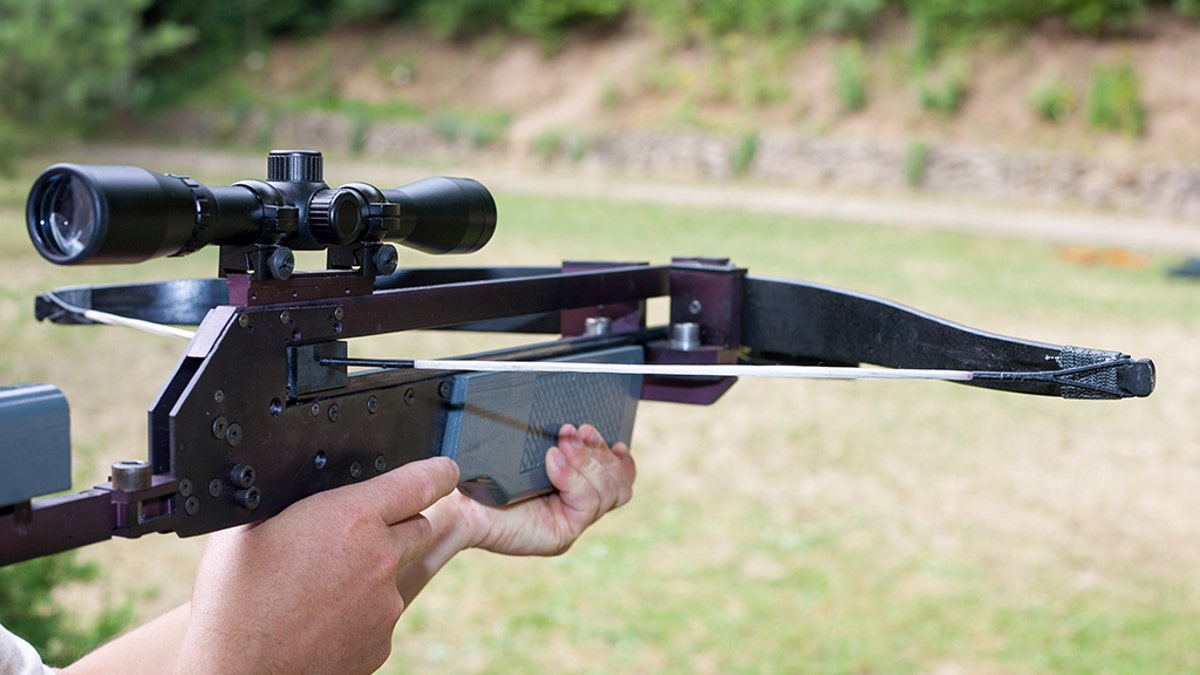 Man holding a scoped crossbow.