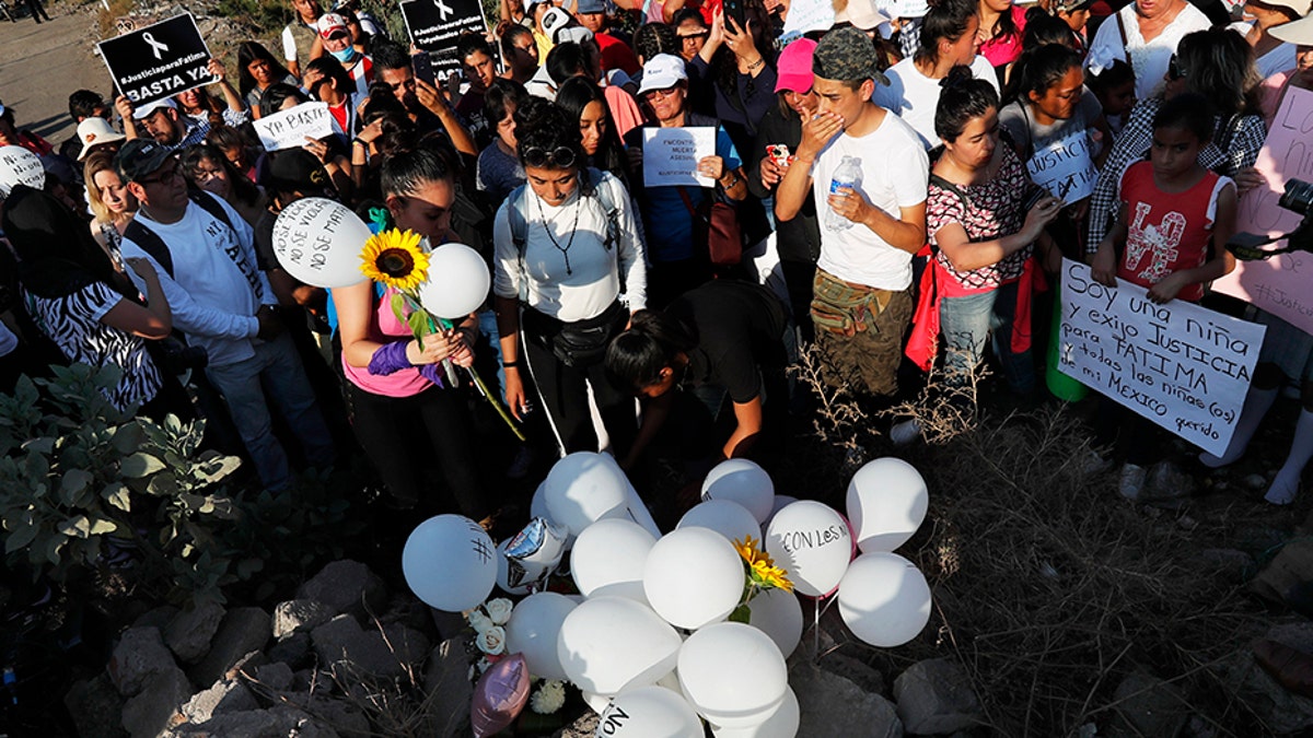 Demonstrators set a up a memorial with flowers, balloons and candles at the site where the body of Fatima was found.