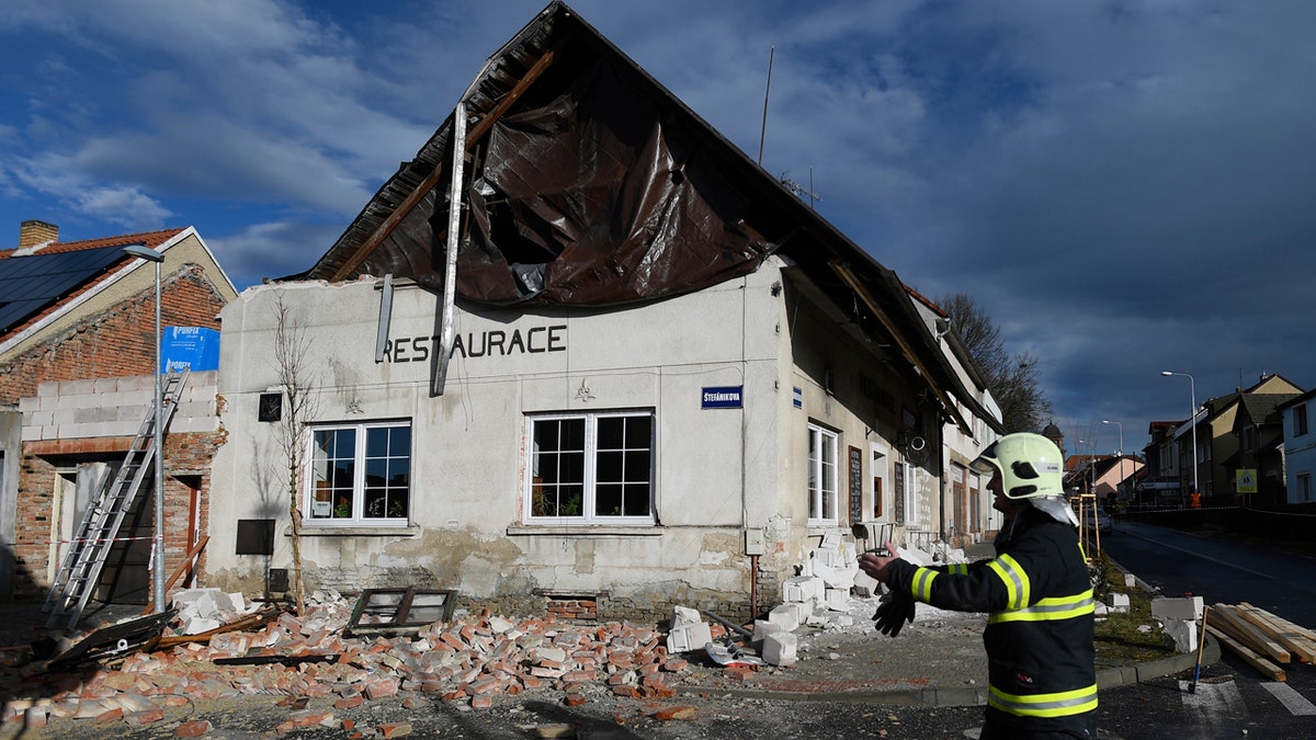 A fireman passes by a house which roof was moved due to a strong storm in Kladno, Czech Republic, Monday, Feb. 10, 2020. 