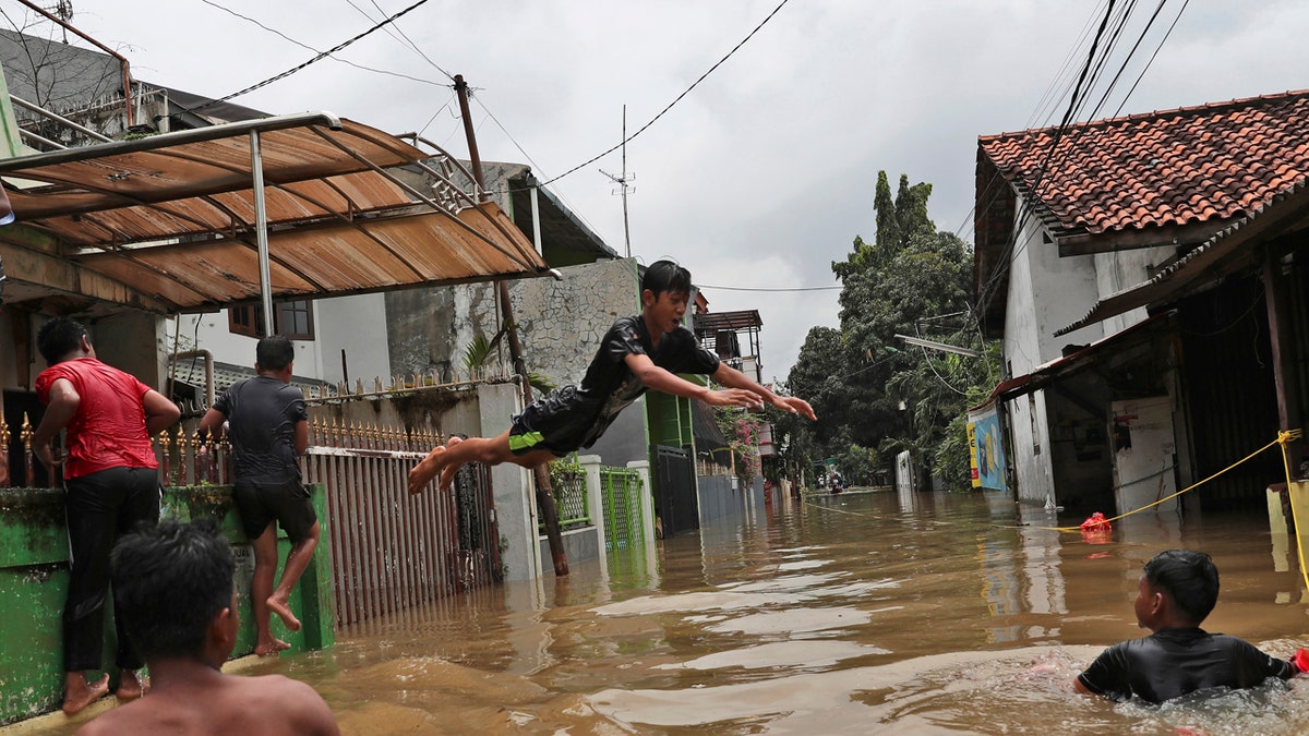 Indonesian youths play in flood water in a neighborhood in Jakarta, Indonesia, Tuesday, Feb. 25, 2020.