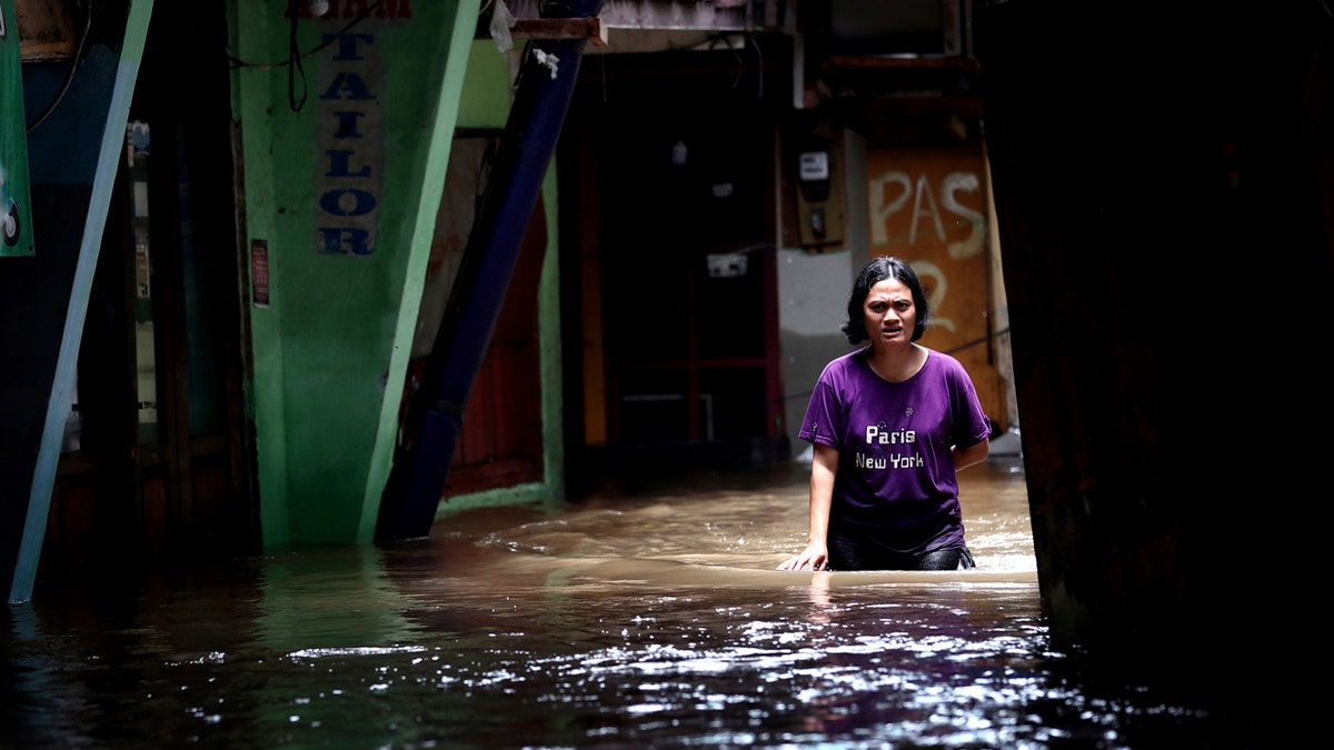 A woman wades through water in a flooded neighborhood in Jakarta, Indonesia, Tuesday, Feb. 25, 2020.