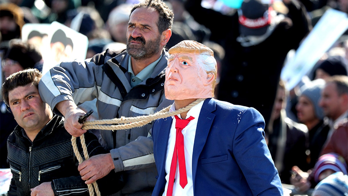 A protester pulls a rope around the neck of a man impersonating President Trump during a rally in Tehran Tuesday. (AP)