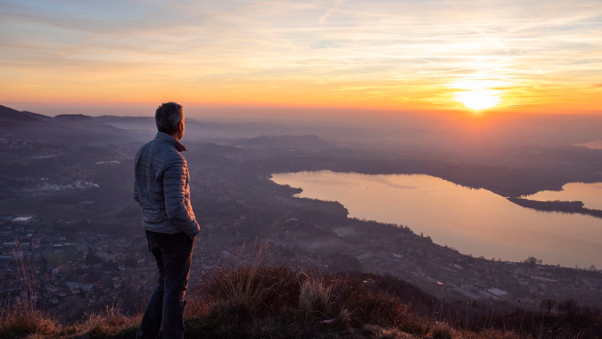 Hiker looking sun over horizon