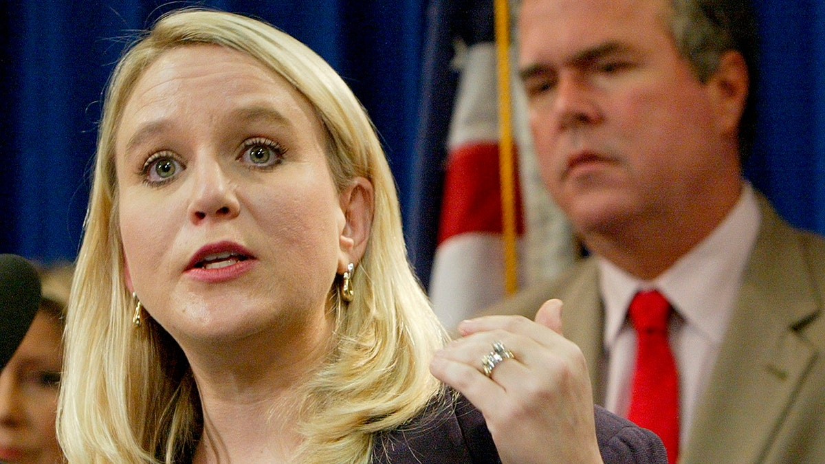 Tiffany Carr, then the executive director of Florida Coalition Against Domestic Violence, left, speaks at a news conference held by Gov. Jeb Bush, background right, Sept. 28, 2004, in Tallahassee, Fla. (Associated Press)
