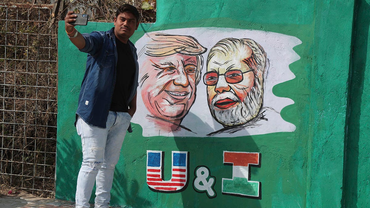 A man takes a selfie with portraits of U.S. President Donald Trump and Indian Prime Minister Narendra Modi painted on a wall ahead of Trump's visit, in Ahmedabad, India, Tuesday, Feb. 18, 2020. Trump is scheduled to visit the city during his Feb. 24-25 India trip. (AP Photo/Ajit Solanki)