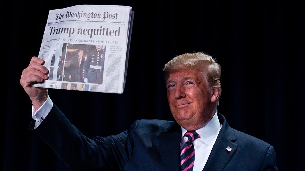 President Donald Trump holds up a newspaper with the headline that reads "Trump acquitted" during the 68th annual National Prayer Breakfast, at the Washington Hilton, Thursday, Feb. 6, 2020, in Washington. (AP Photo/ Evan Vucci)