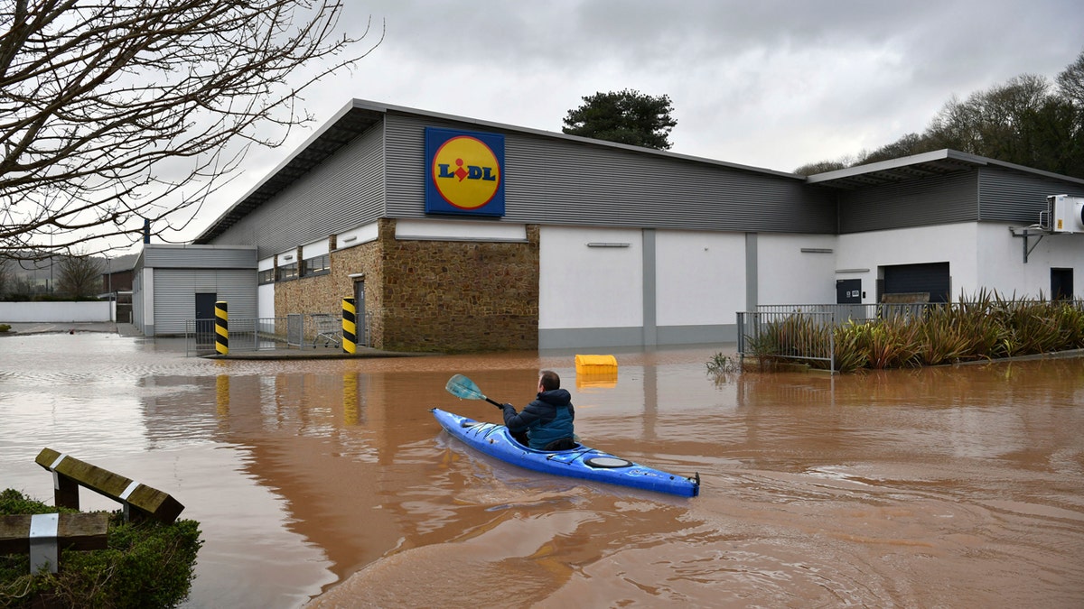 A man travels by boat through floodwater in Monmouth, Wales, Tuesday Feb. 18, 2020.