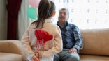 Cute little girl celebrating Valentine's day with parents, family and herself, holding heart shape decorations, home interior.