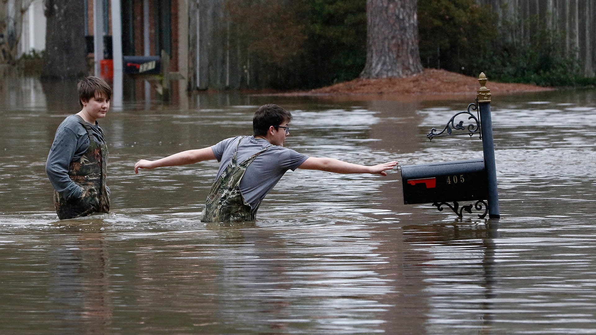 Blaine Henderson reaches out to a mailbox as he and Jonah Valdez play in the Pearl River floodwaters in Jackson, Miss., Sunday.