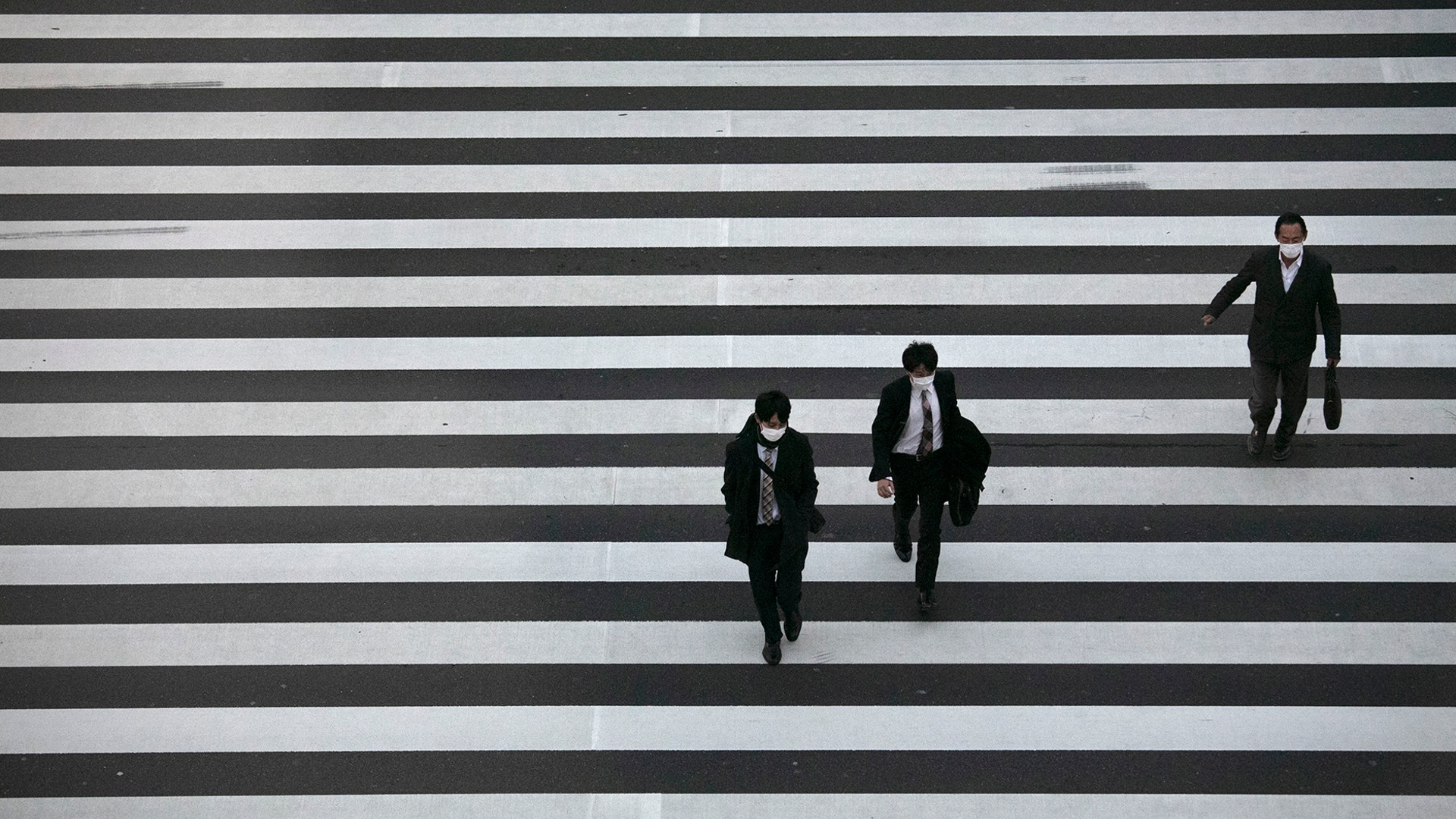 Commuters wearing masks walk across a pedestrian crosswalk in Tokyo, Feb. 26, 2020.