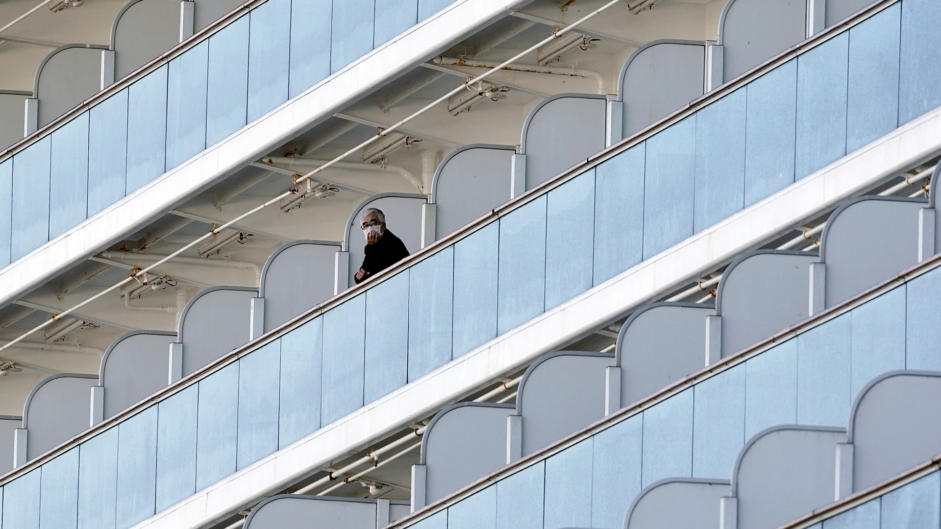 A passenger stands on a balcony of the Diamond Princess cruise ship anchored at the Yokohama Port in Yokohama, Japan, Feb. 6, 2020.