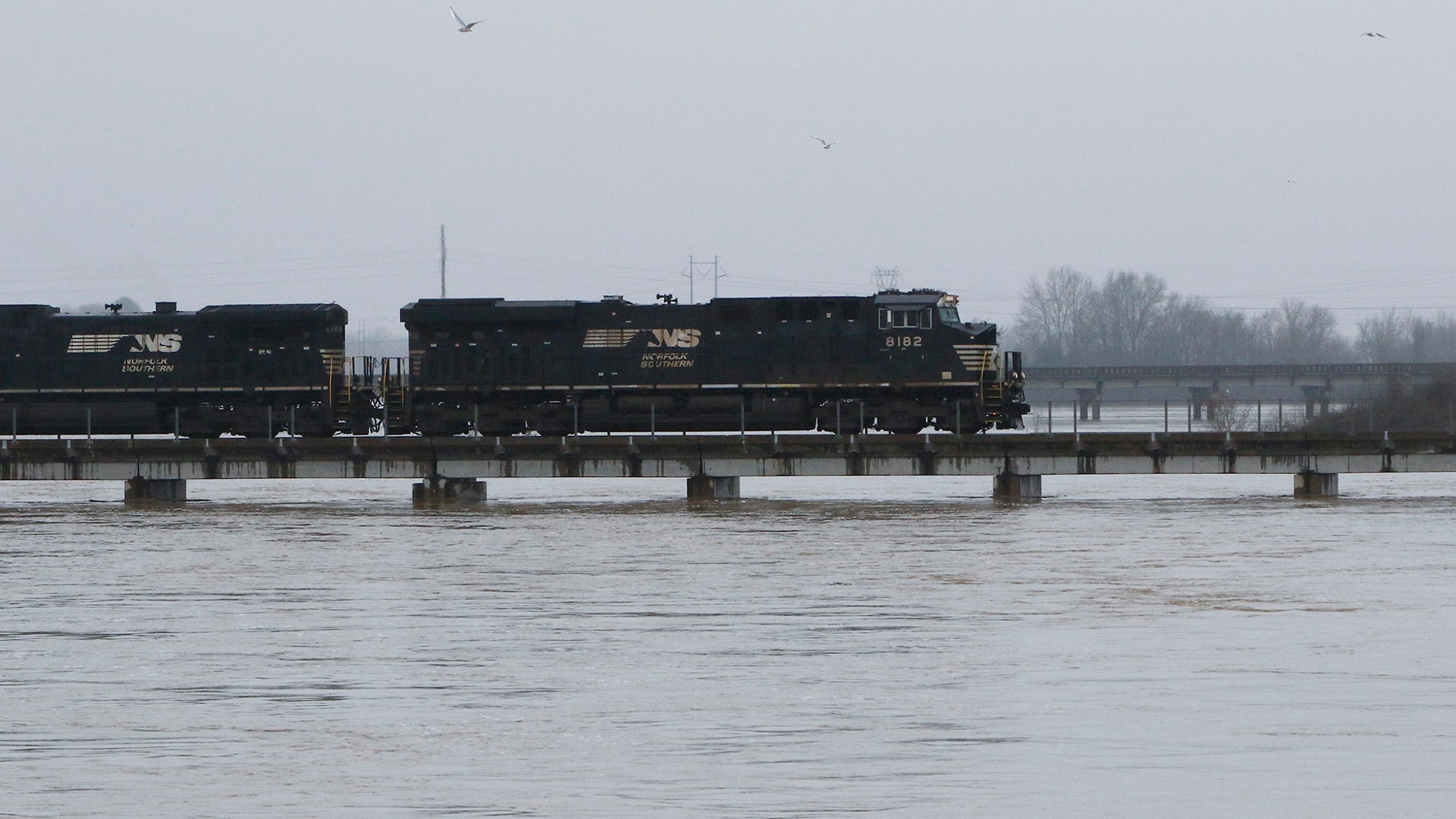 A freight train rolls over the swollen Pearl River towards Jackson, Miss., Sunday.