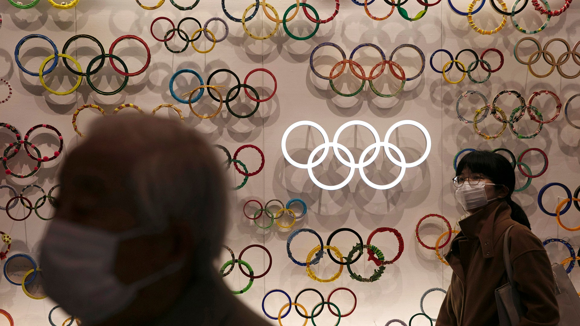 Two people wear masks as they visit the newly opened Japan Olympic Museum located near the New National Stadium, in Tokyo, Feb. 23, 2020. 